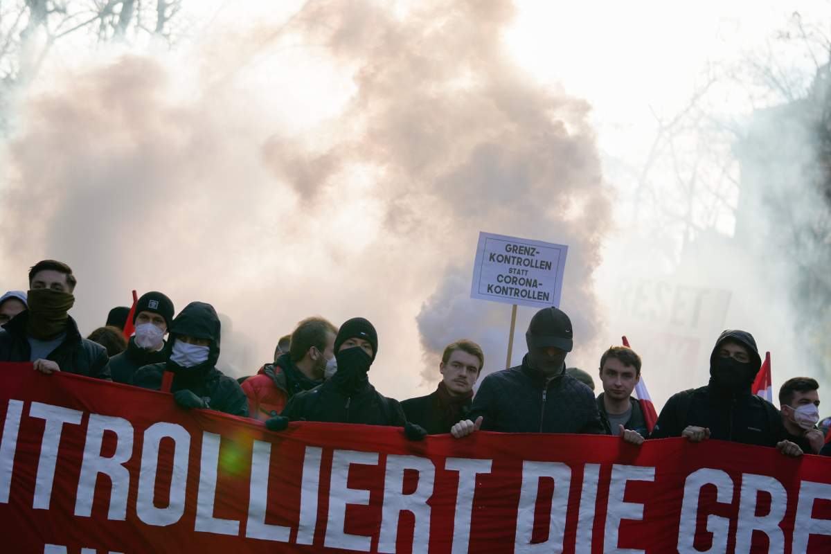 Protestors with a banner ‘Control the borders’ attend a demonstration against measures to battle the coronavirus pandemic in Vienna, Austria, Saturday, Nov. 20, 2021. (AP Photo/Florian Schroetter)