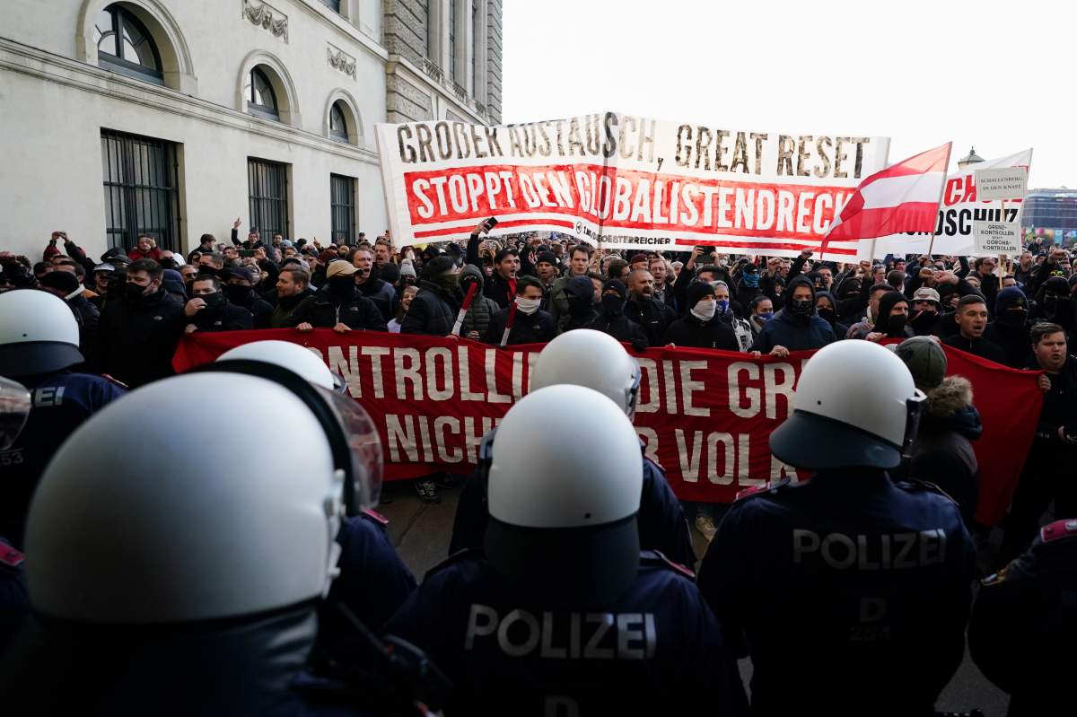 Police officers stand on front of protestors during a demonstration against measures to battle the coronavirus pandemic in Vienna, Austria, Saturday, Nov. 20, 2021. (AP Photo/Florian Schroetter)