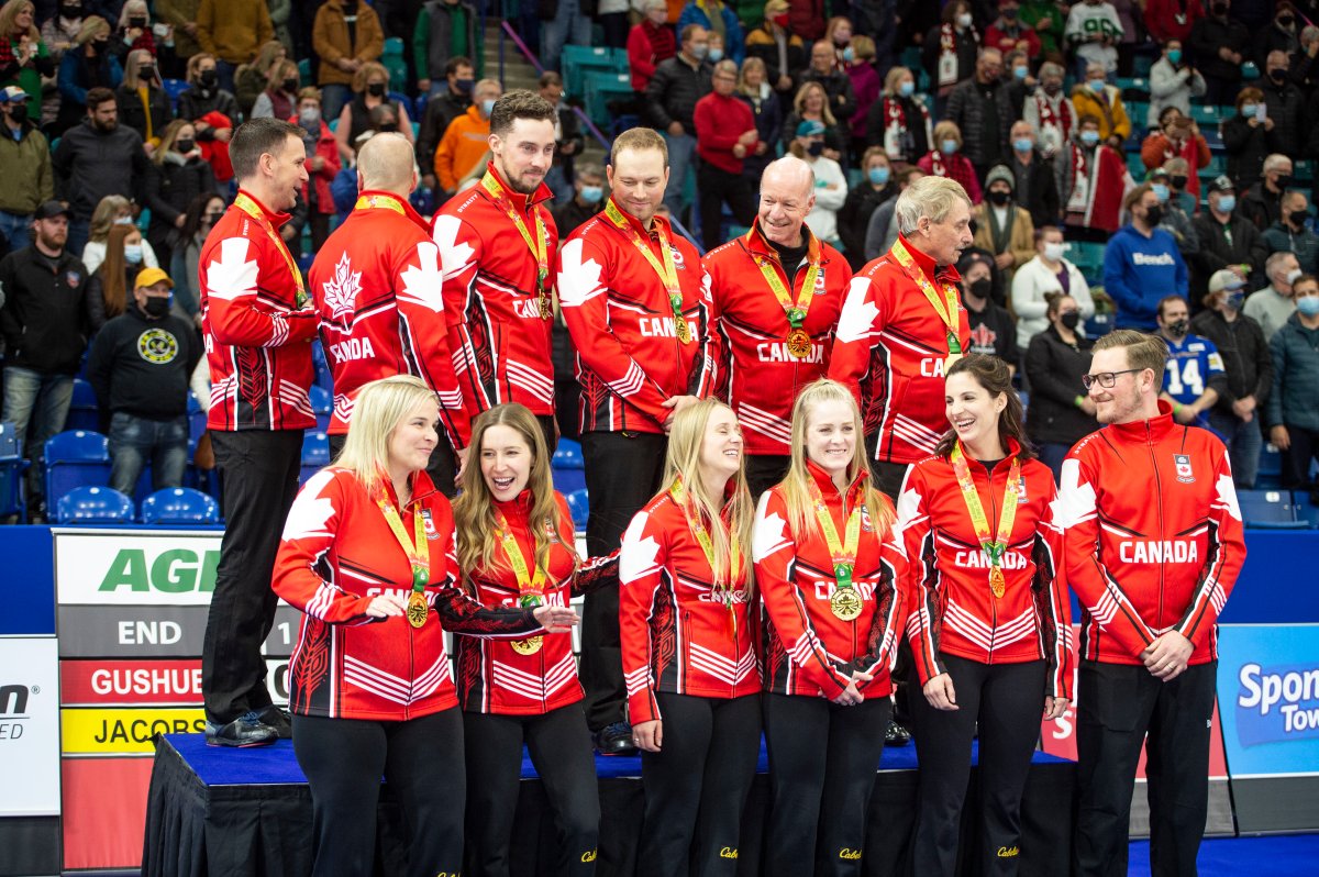 Team Jones and Team Gushue meet at the podium for a Team Canada photo after the men's final of the 2021 Canadian Olympic curling trials, in Saskatoon on Nov. 28, 2021.