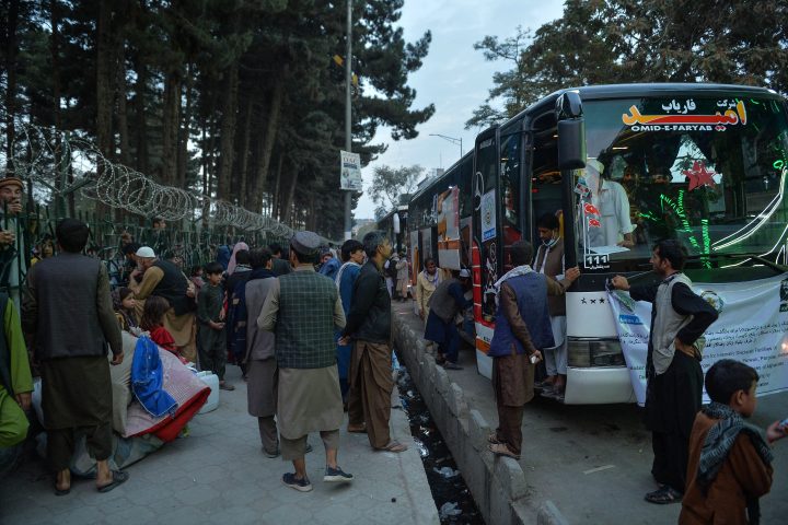 Internally displaced people with their belongings wait to board a bus to reach their native places with the aid of an Non Governmental Organisation (NGO) and the Taliban in Kabul on September 29, 2021. (Photo by Hoshang Hashimi / AFP) .