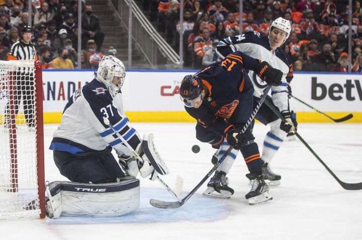 Winnipeg Jets’ Connor Hellebuyck (37) makes the save on Edmonton Oilers’ Jesse Puljujarvi (13) as Logan Stanley (64) defends during second period NHL action in Edmonton on Thursday, November 18, 2021.
