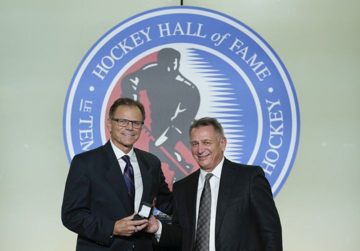 Mike Gartner, left, gives a ring to Hockey Hall of Fame inductee Ken Holland in Toronto, Friday, Nov. 12, 2021.