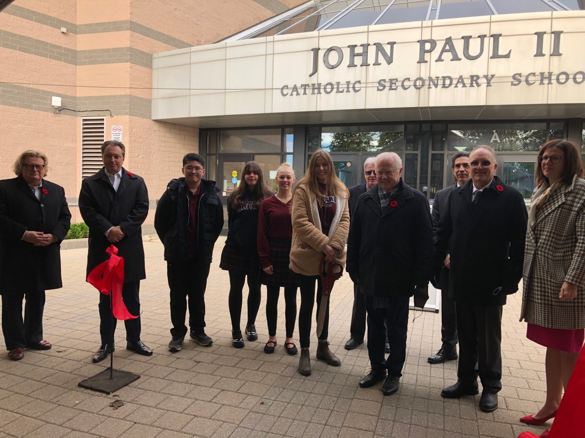Officials join a ribbon cutting ceremony outside of John Paul II Catholic Secondary School to mark the school's newly minted carbon neutral status.