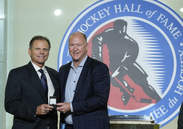 Mike Gartner, left, gives a ring to Hockey Hall of Fame inductee Kevin Lowe in Toronto, Friday, Nov. 12, 2021.