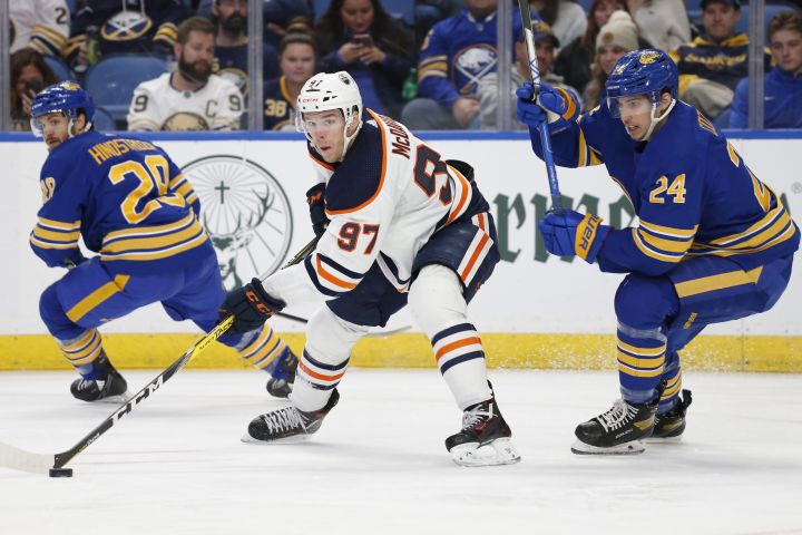 Edmonton Oilers centre Connor McDavid (97) carries the puck past Buffalo Sabres centre Dylan Cozens (24) during the second period of an NHL hockey game, Friday, Nov. 12, 2021, in Buffalo, N.Y.