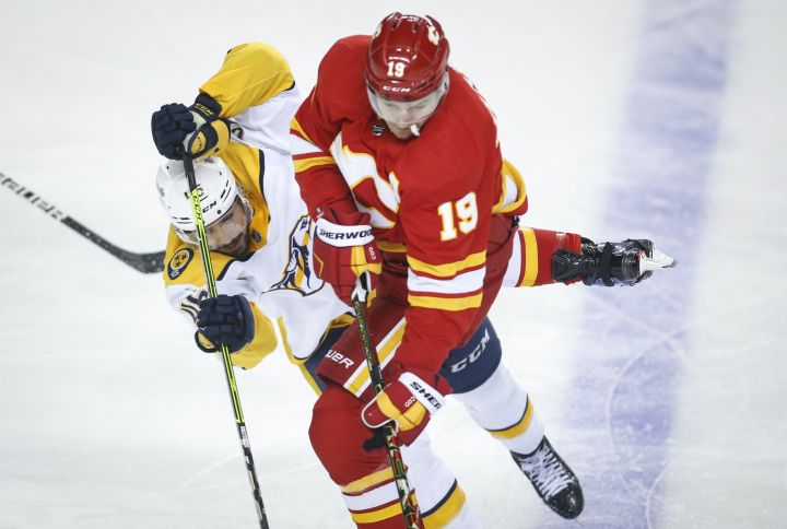 Nashville Predators’ Alexandre Carrier, left, is checked by Calgary Flames’ Matthew Tkachuk during first period NHL hockey action in Calgary, Tuesday, Nov. 2, 2021.