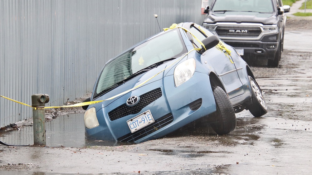 A Toyota Yaris parked along Grace Rd in Surrey ended up in a small sinkhole after the side of the road gave way.