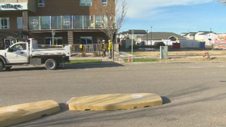 City workers install a new crosswalk and traffic calming curbs in front of Harbour Landing Village in Regina.
