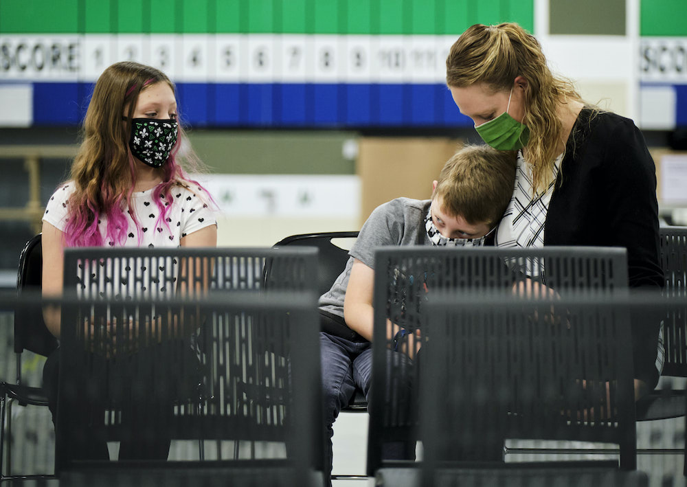 Danielle Vernooy, sits with her kids, Julie, left and Eric while they wait for their COVID-19 vaccine inside the COVID-19 vaccination clinic at the Nepean Sportsplex in Ottawa Friday, November 26, 2021.