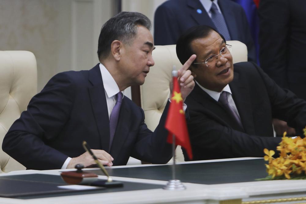 FILE - Chinese Foreign Minister Wang Yi, left, talks with Cambodian Prime Minister Hun Sen as they sit to witness a signing ceremony for a free trade agreement at Peace Palace in Phnom Penh, Cambodia, Monday, Oct. 12, 2020. The U.S. has ordered an arms embargo on Cambodia, citing deepening Chinese military influence, corruption and human rights abuses by the government and armed forces in the Southeast Asian country. (AP Photo/Heng Sinith, File).
