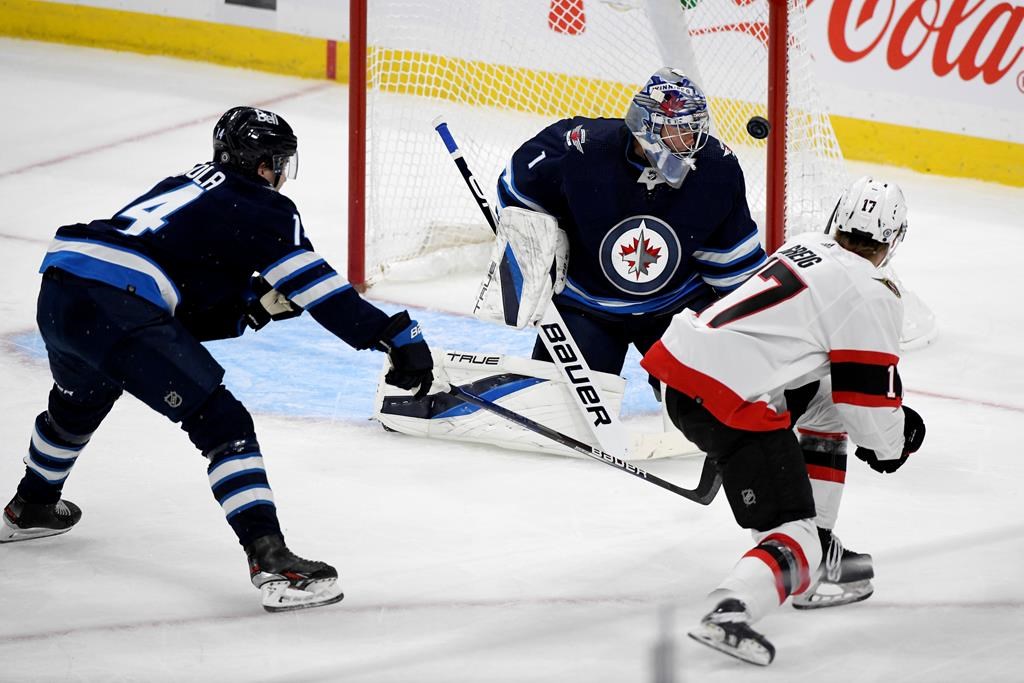 The Ottawa Senators’ Ridly Greig (17) scores on Winnipeg Jets goaltender Eric Comrie (1) during first-period NHL preseason action in Winnipeg, Sunday, Sept. 26, 2021.  THE CANADIAN PRESS/Fred Greenslade