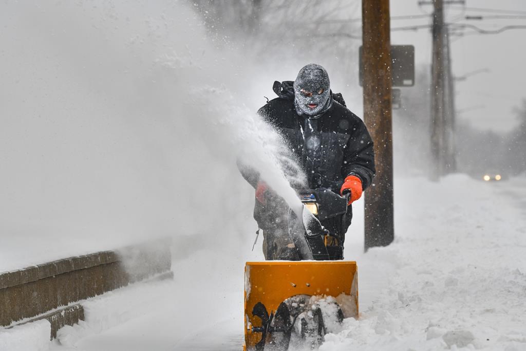 FILE - A man uses a snow blower on a sidewalk Monday, Dec. 27, 2021.