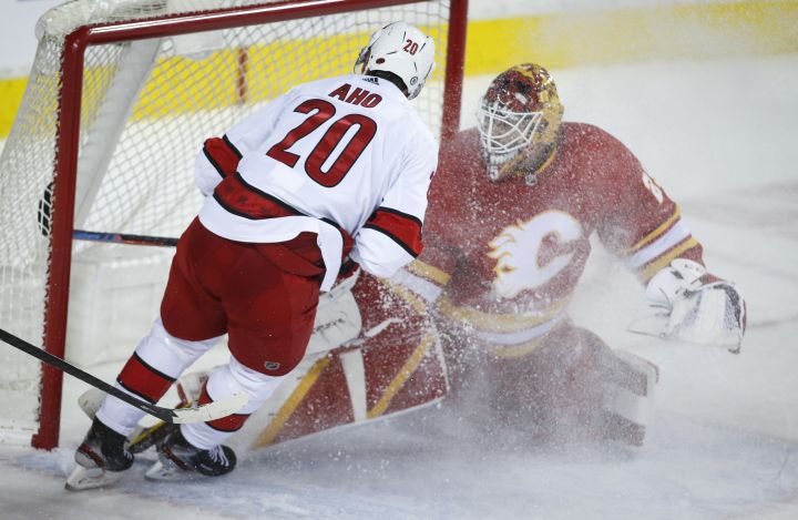 Carolina Hurricanes’ Sebastian Aho, left, scores the game-winning goal on Calgary Flames goalie Jacob Markstrom during overtime NHL hockey action against the Calgary Flames in Calgary, Thursday, Dec. 9, 2021.