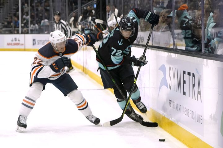 Edmonton Oilers defenseman Tyson Barrie (22) reaches across Seattle Kraken right wing Joonas Donskoi toward the puck during the first period of an NHL hockey game Friday, Dec. 3, 2021, in Seattle.