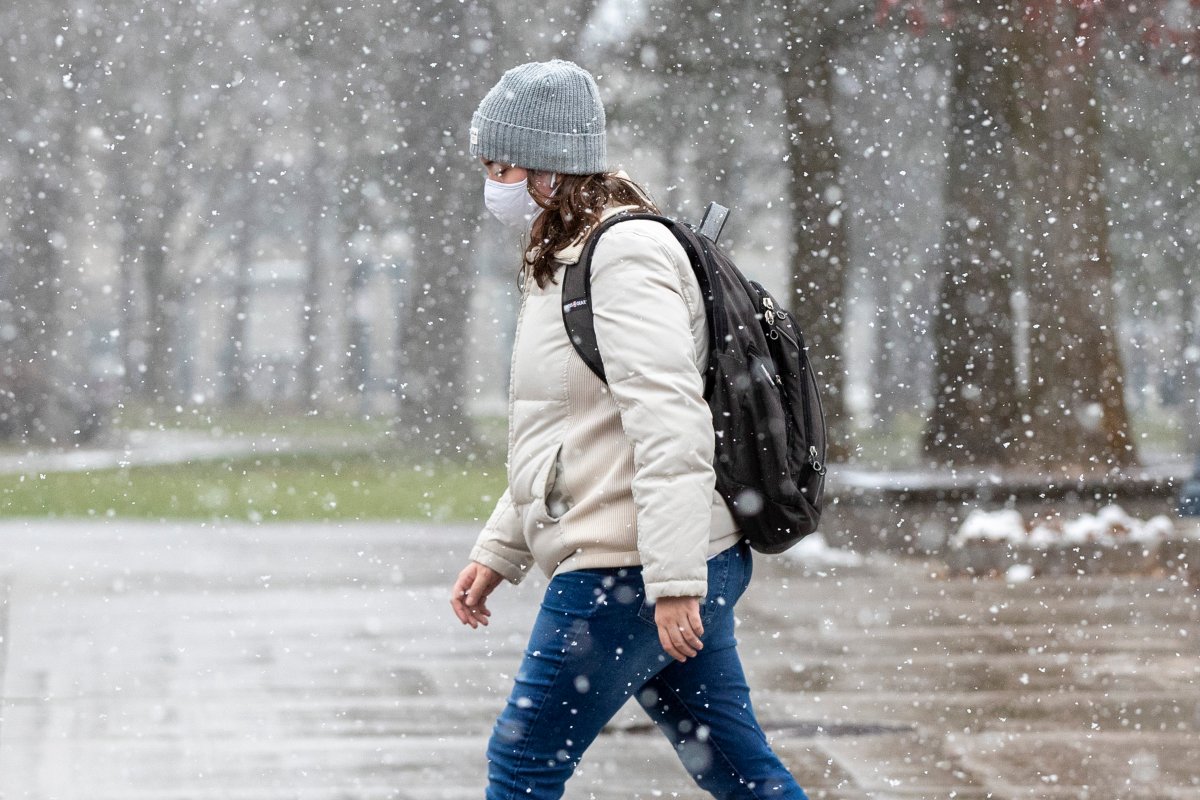 A person wears a mask to protect them from the COVID-19 virus during snow squall in Kingston, Ontario on Tuesday November 30, 2021. 