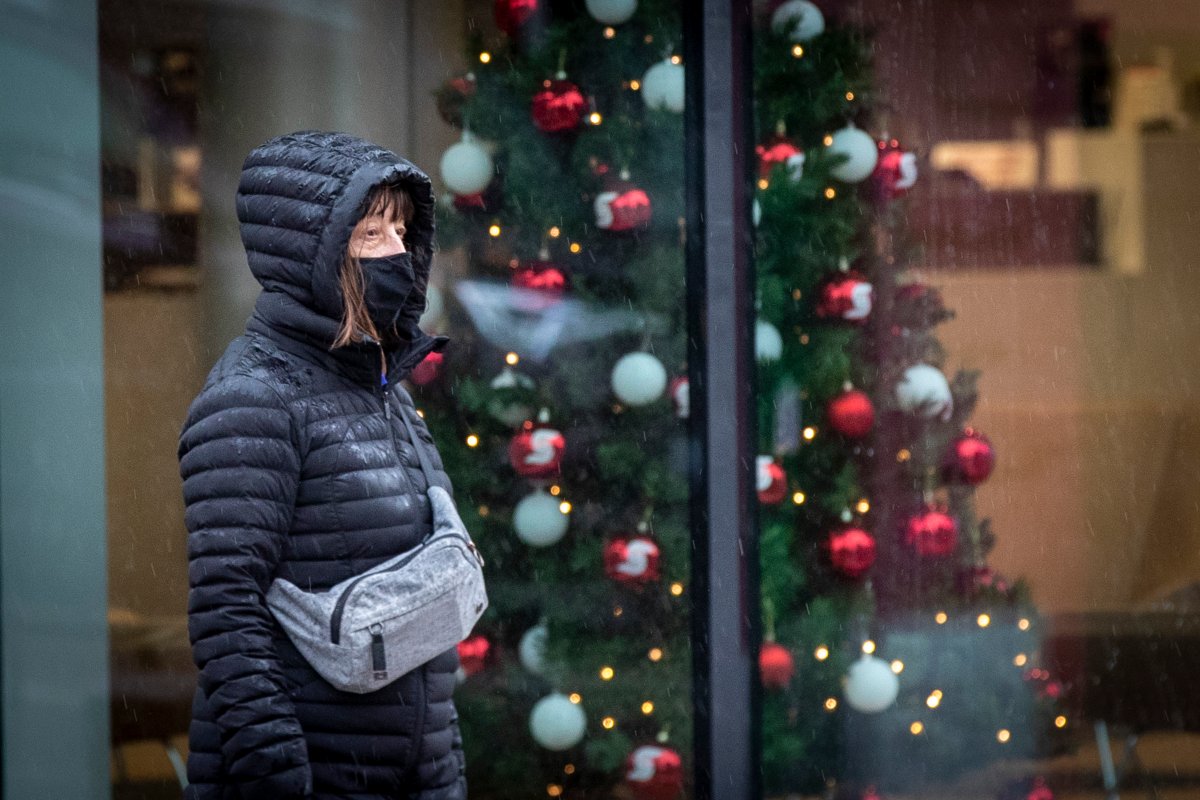 A person wears a mask to protect them from COVID-19 while walking past a Christmas tree in a store on Wednesday, Dec. 15, 2021.