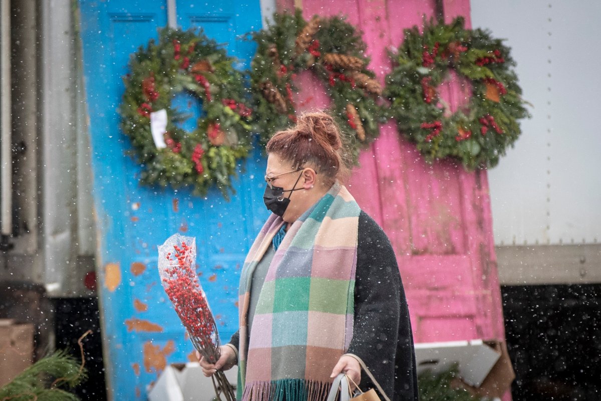 A person wears a surgical mask to protect them from the COVID-19 virus while walking by Christmas decorations at a farmers market in Kingston, Ontario on Tuesday November 30, 2021.