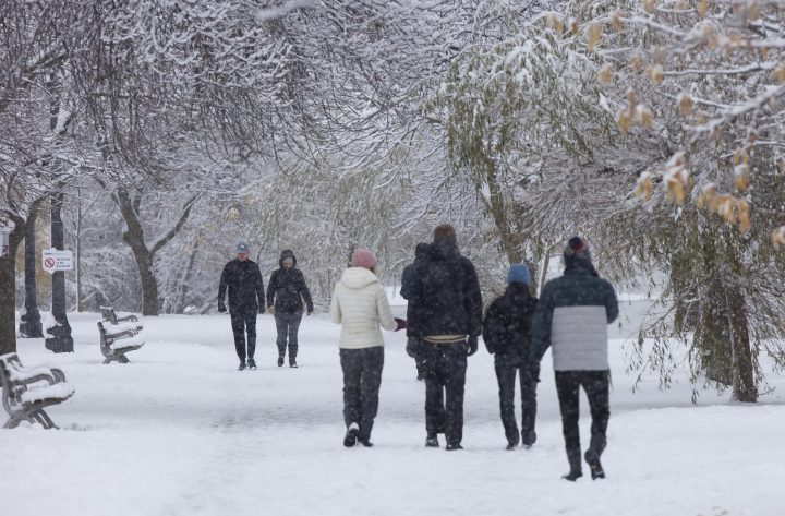 People walk in the snow during a snowy day in a park in Toronto on Nov. 28, 2021.