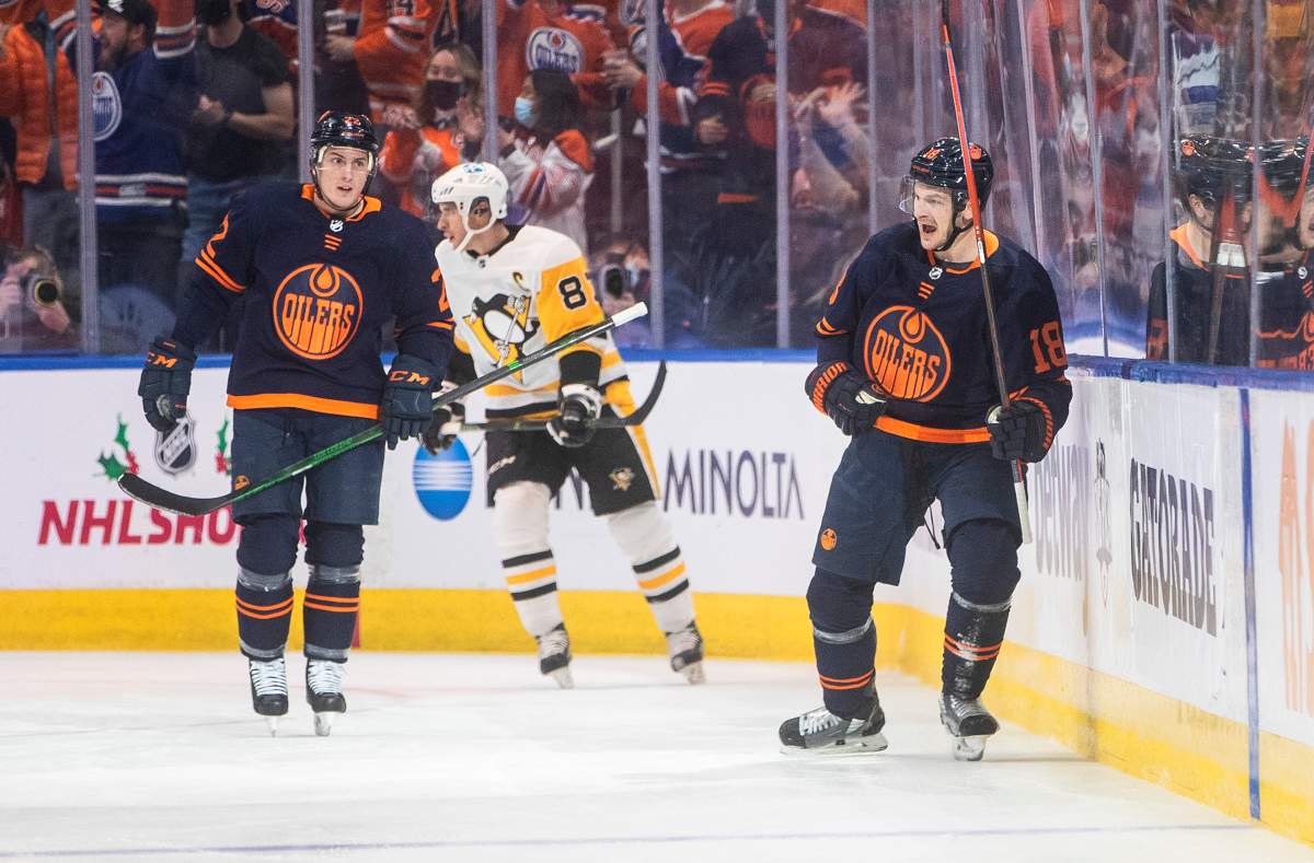 Pittsburgh Penguins’ Sidney Crosby (87) skates past as Edmonton Oilers’ Tyson Barrie (22) and Zach Hyman (18) celebrate a goal during first period NHL action in Edmonton on Wednesday, December 1, 2021.