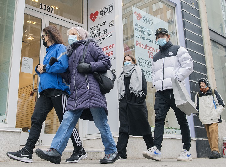 People walk by a COVID-19 rapid testing business in Montreal, Saturday, Dec. 4, 2021. 