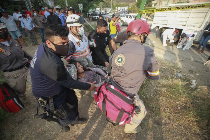 An injured migrant woman is moved by rescue personnel from the site of an accident near Tuxtla Gutierrez, Chiapas state, Mexico, Dec. 9, 2021. Mexican authorities say at least 49 people were killed and dozens more injured when the truck carrying the migrants rolled over on the highway in southern Mexico.