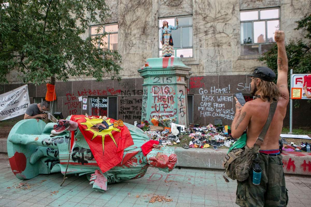 People stand around the plinth after protesters pulled down the statue of Egerton Ryerson at Ryerson University, in Toronto on Sunday, June 6, 2021. Ryerson was the chief superintendent of education for Upper Canada and his recommendations were regarded as instrumental in the design and implementation of the Indian Residential School System.