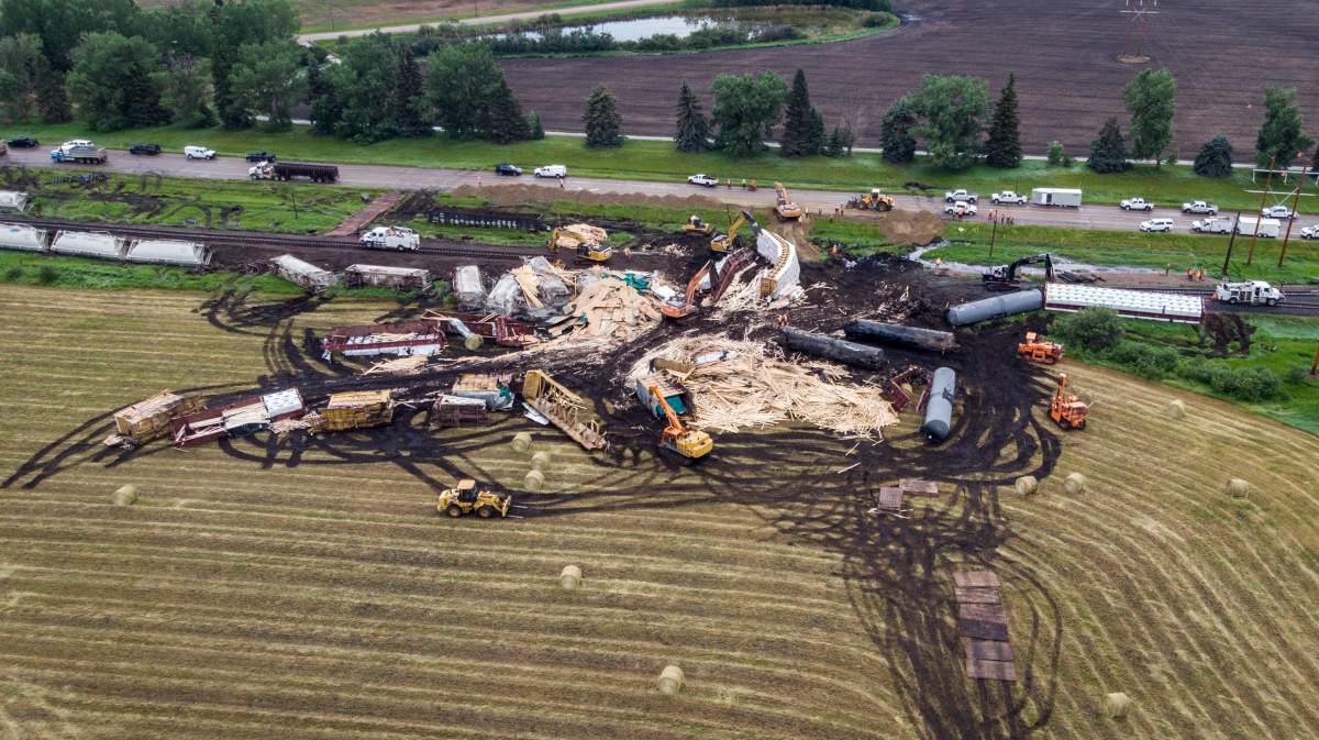 Crews work to clean up a spill after the derailment of a 20-car train carrying "tar sand'' and lumber near Blackfalds, Alta., Saturday, July 3, 2021.