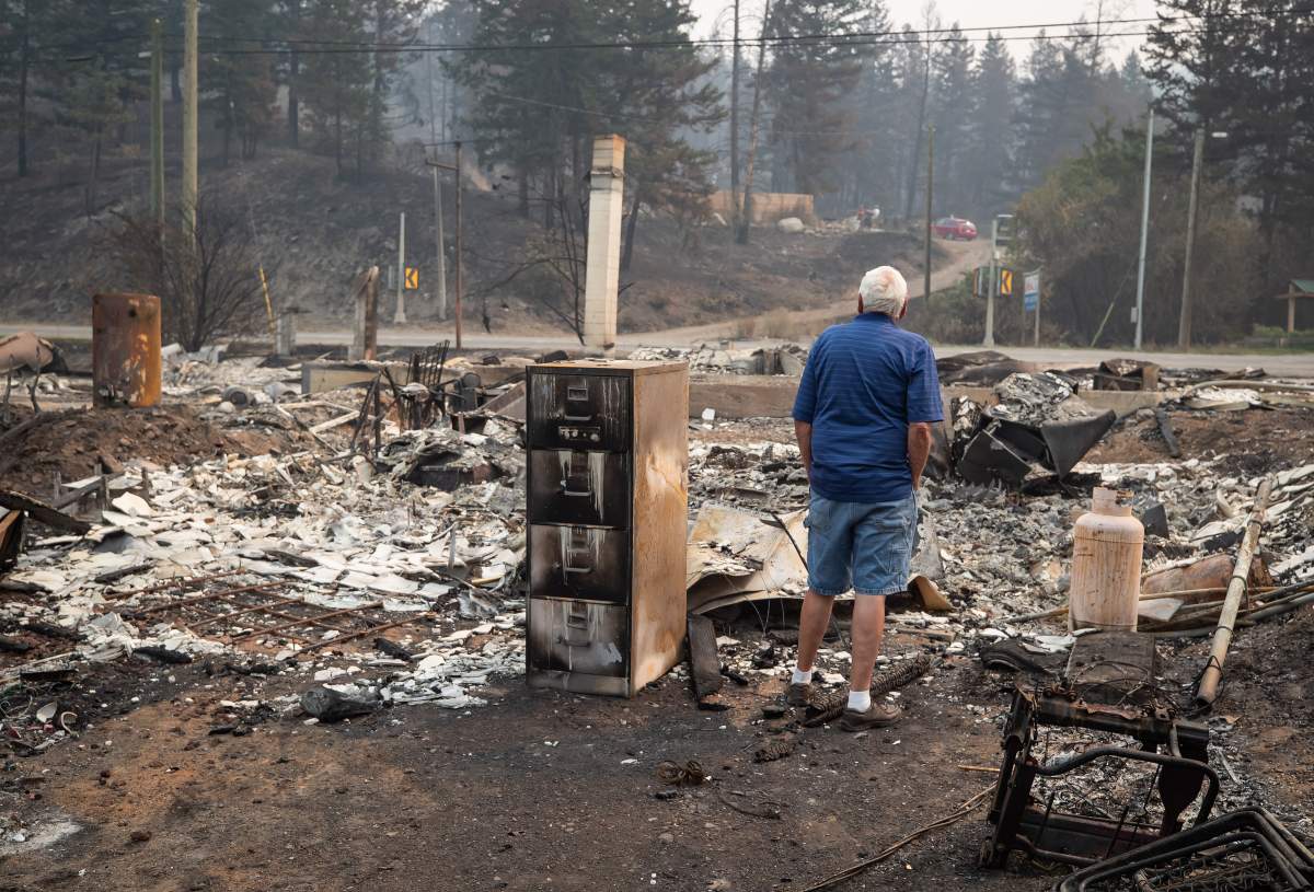 David Wear looks over the remains of a house destroyed by the White Rock Lake wildfire in Monte Lake, east of Kamloops, B.C., Saturday, Aug. 14, 2021. Wear recently sold the property and hadn't been living in it since moving to Merritt, B.C., with his wife in 2018, he said the people who bought the house all were able to escape to safety.