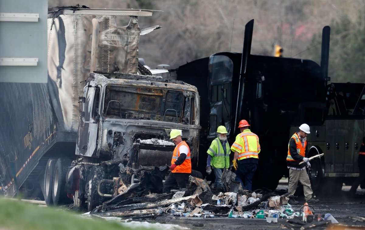FILE - Workers clear debris from the eastbound lanes of Interstate 70 on April 26, 2019, in Lakewood, Colo., following a deadly pileup involving a semi-truck hauling lumber.