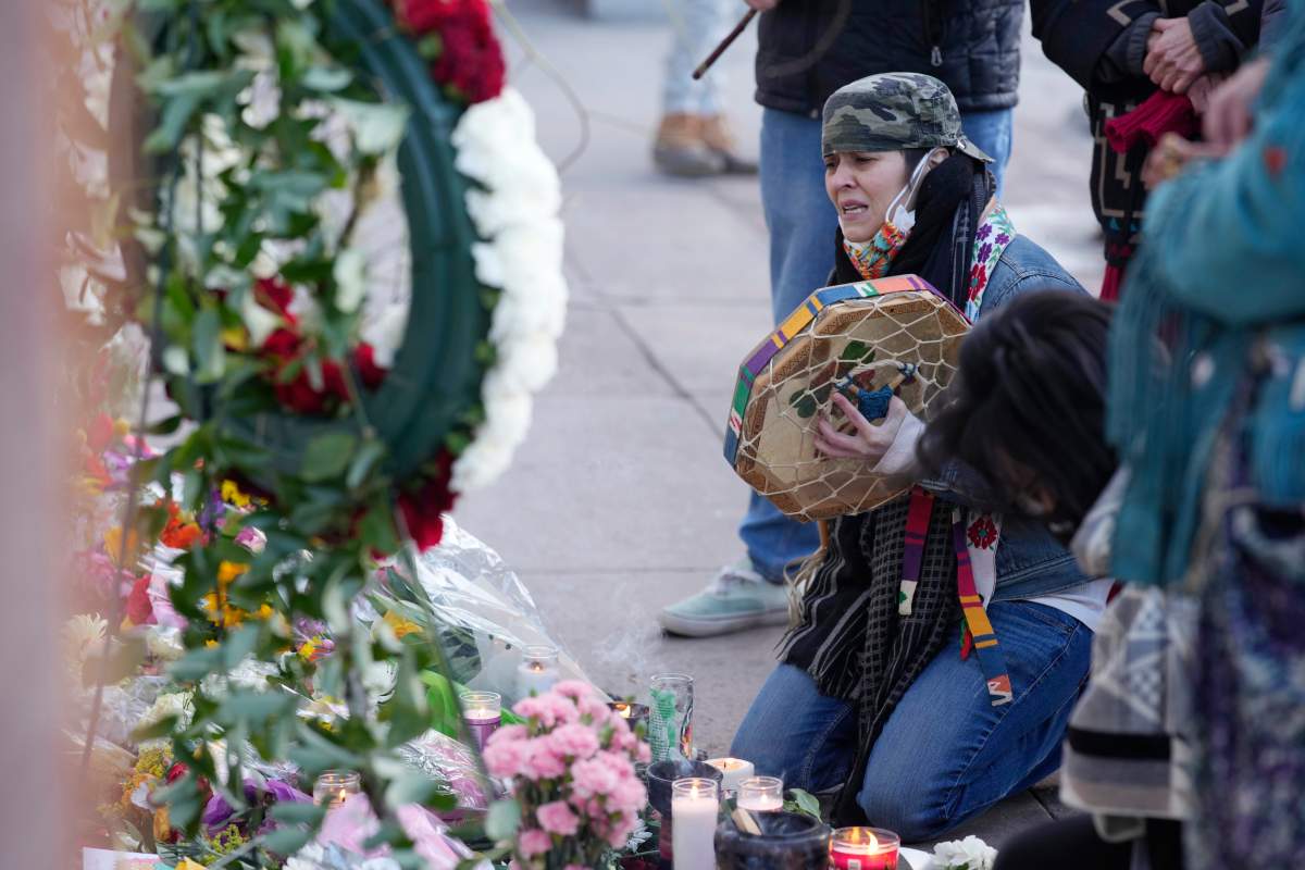 Mourners gather outside the door of a tattoo parlor along South Broadway Tuesday, Dec. 28, 2021, in Denver, one of the scenes of a shooting spree that left multiple people dead, including the suspected shooter Monday evening and a few more people wounded.