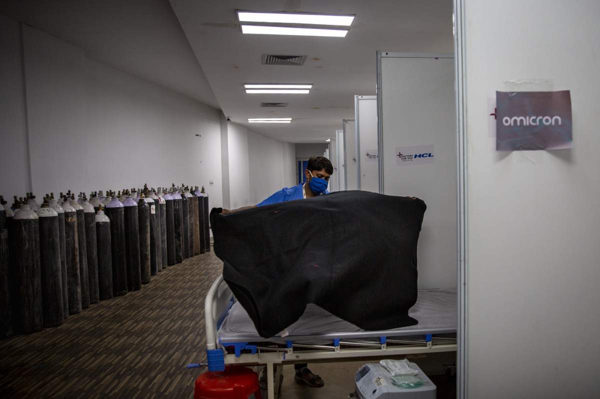 A paramedic make beds at a makeshift COVID-19 care center at an indoor sports stadium in New Delhi, India on Dec. 22, 2021. Caseloads of omicron have remained relatively low in many countries in Asia. For now, many remain insulated from the worst, although the next few months will remain critical. (AP Photo/Altaf Qadri).