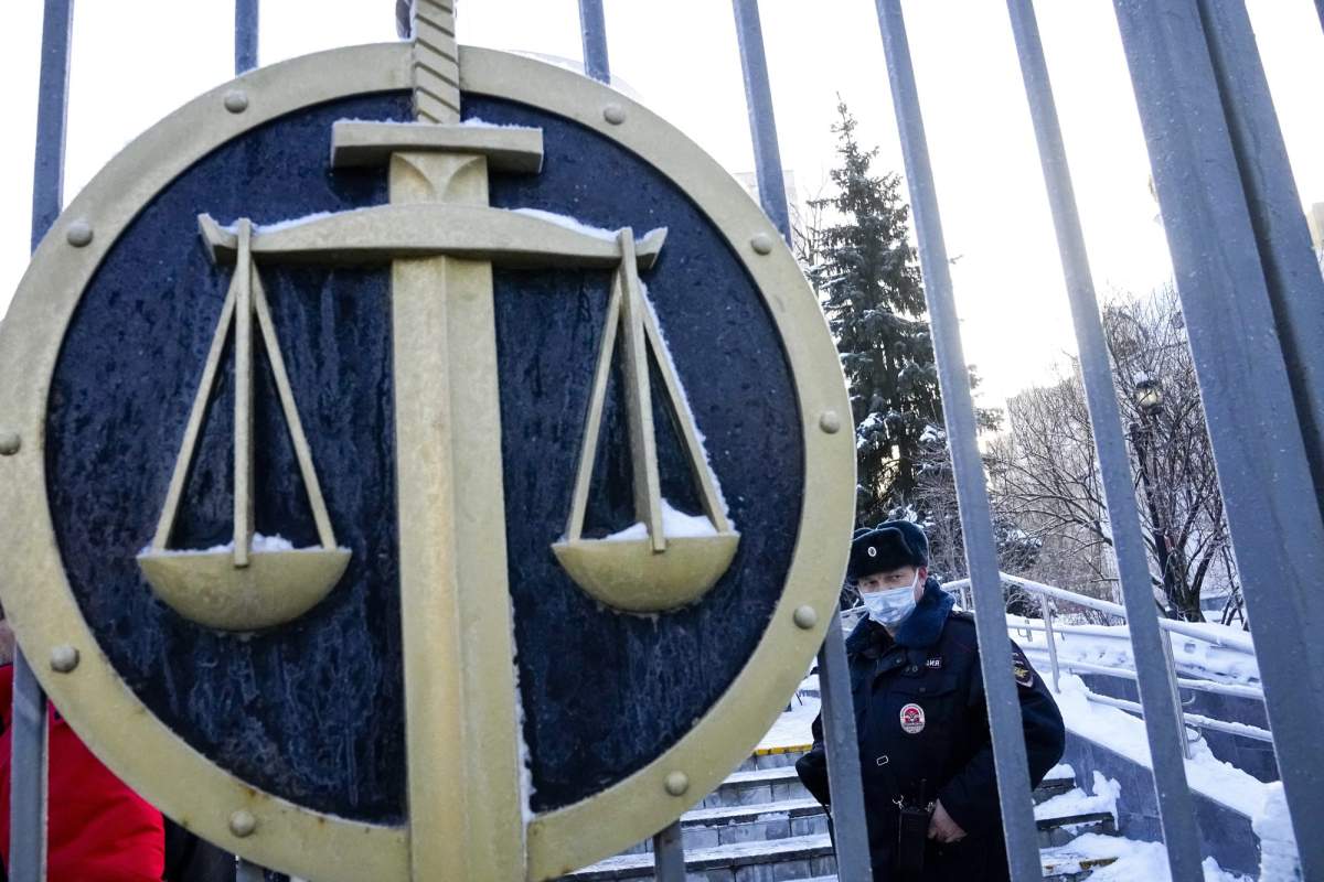 A police officer guards a an entrance of the Moscow Court where supporters of the Memorial human rights group gather in Moscow, Russia, Wednesday, Dec. 29, 2021.A court in Moscow has ruled to shut down another prominent human rights organization amid a sweeping crackdown on Russia's rights groups, independent media and opposition supporters. (AP Photo/Alexander Zemlianichenko).