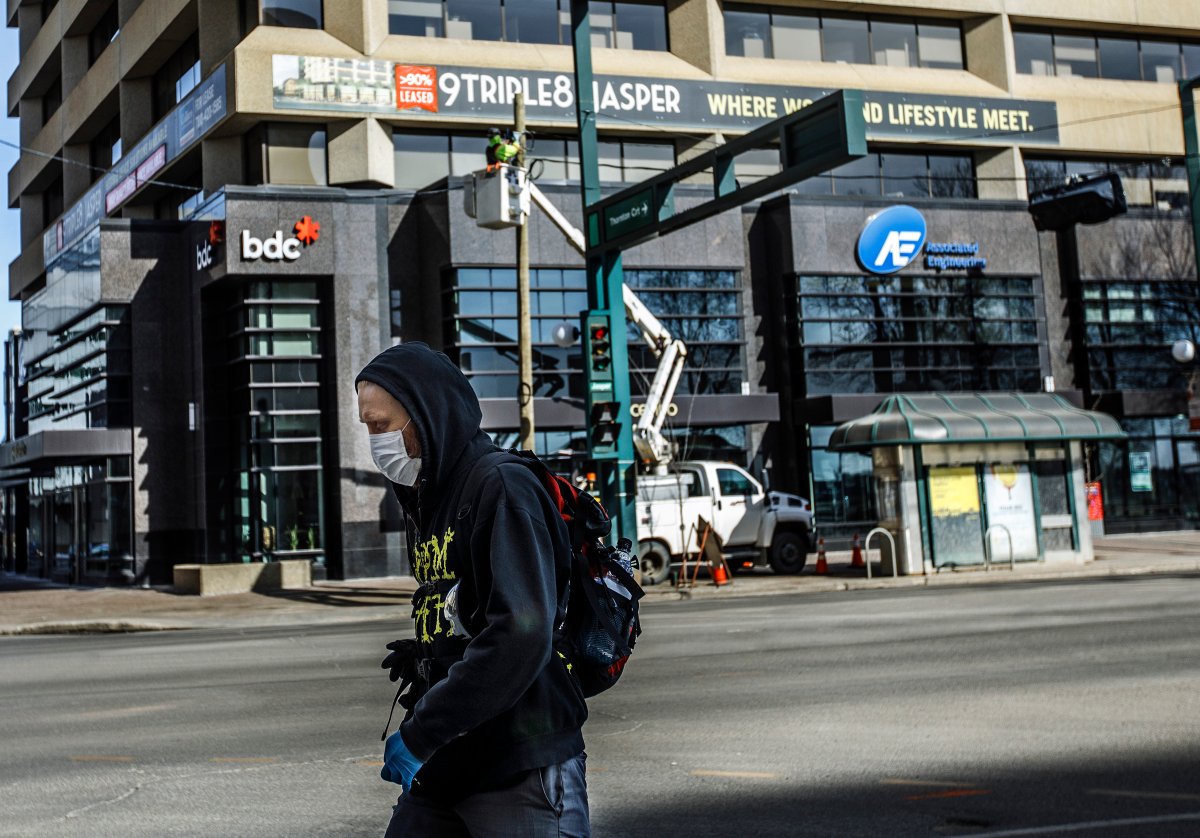 A pedestrian wearing a mask walks down the empty streets of downtown Edmonton on Sunday March 22, 2020. 