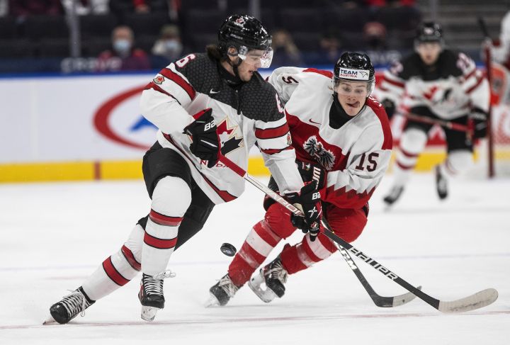 Canada’s Lukas Cormier (6) and Austria’s Fin van Ee (15) battle for the puck during first period IIHF World Junior Hockey Championship action in Edmonton on Tuesday, December 28, 2021.