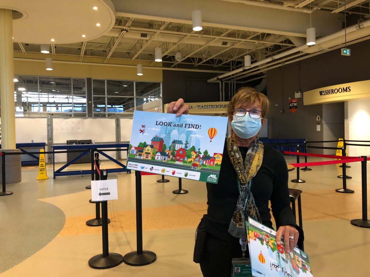Senior manager of COVID-19 vaccine clinics for the MLHU Tracey Gordon holds up a 'look and find' chart, which is one of several distraction tools available for kids at the Western Fair District Agriplex clinic.