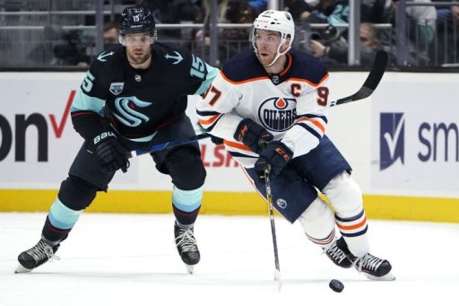 Edmonton Oilers center Connor McDavid (97) skates with the puck ahead of Seattle Kraken center Riley Sheahan (15) during the second period of an NHL hockey game Friday, Dec. 3, 2021, in Seattle.