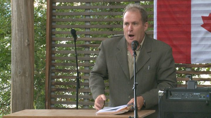 The main organizer for the freedom rally group stands at a podium and gives a speech.