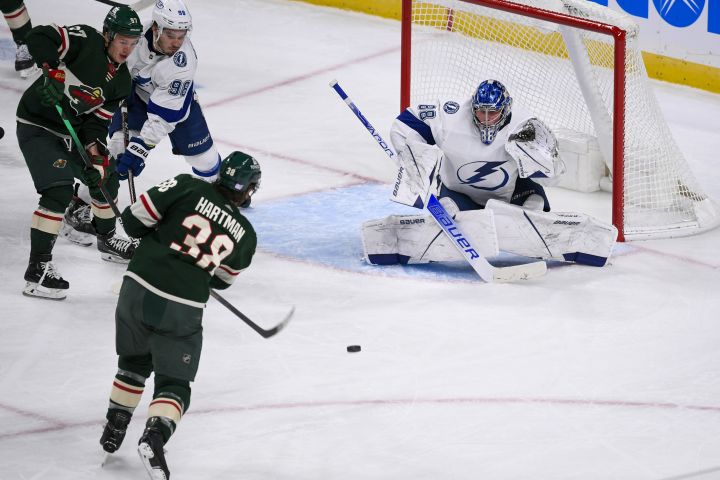 Minnesota Wild right wing Ryan Hartman (38) shoots a puck at Tampa Bay Lightning goalie Andrei Vasilevskiy as Wild left wing Kirill Kaprizov, left, and Lightning defenseman Mikhail Sergachev look on during the third period of an NHL hockey game Sunday, Nov. 28, 2021, in St. Paul, Minn.