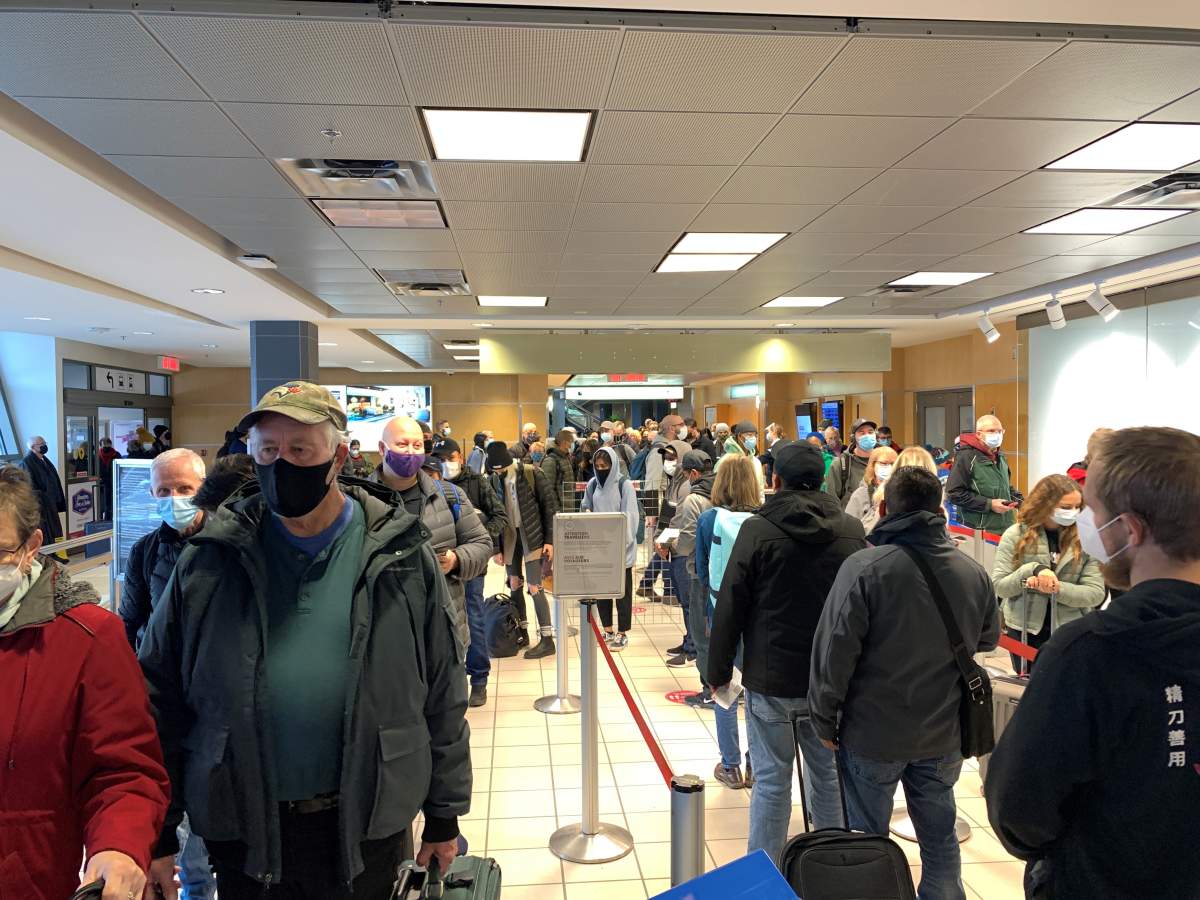 Passengers wait in the security line after being allowed to re-enter the terminal building following a false alarm at YLW on Saturday.