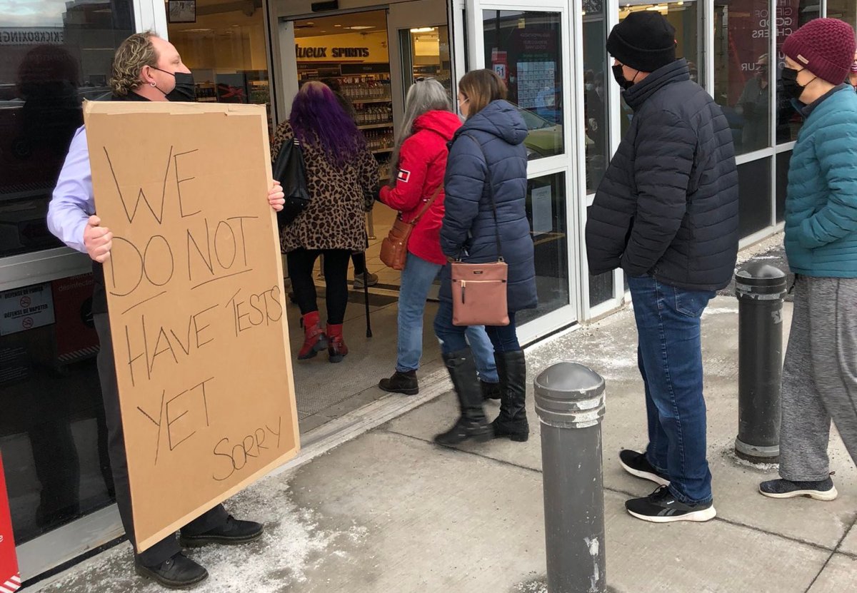 An LCBO worker holds a sign telling customers there are no rapid COVID-19 tests at the Bank Street and Walkley Road location on Friday, Dec. 17, 2021.