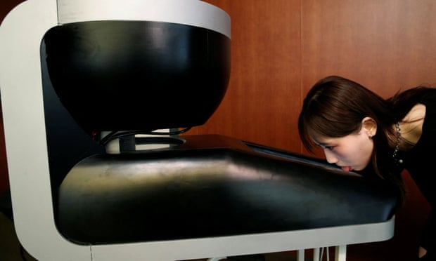 A demonstrator licks the screen of Taste the TV (TTTV), a prototype lickable TV screen that can imitate the flavours of various foods, during its demonstration at the university in Tokyo, Japan, December 22, 2021.