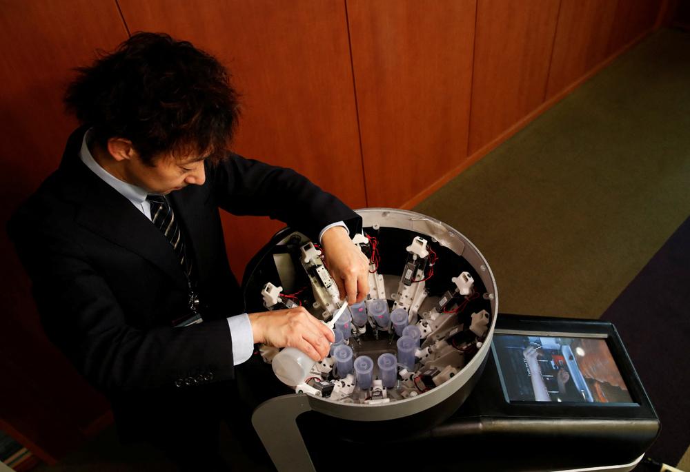 Meiji University professor Homei Miyashita fills flavour canisters as he demonstrates Taste the TV (TTTV), a prototype lickable TV screen.