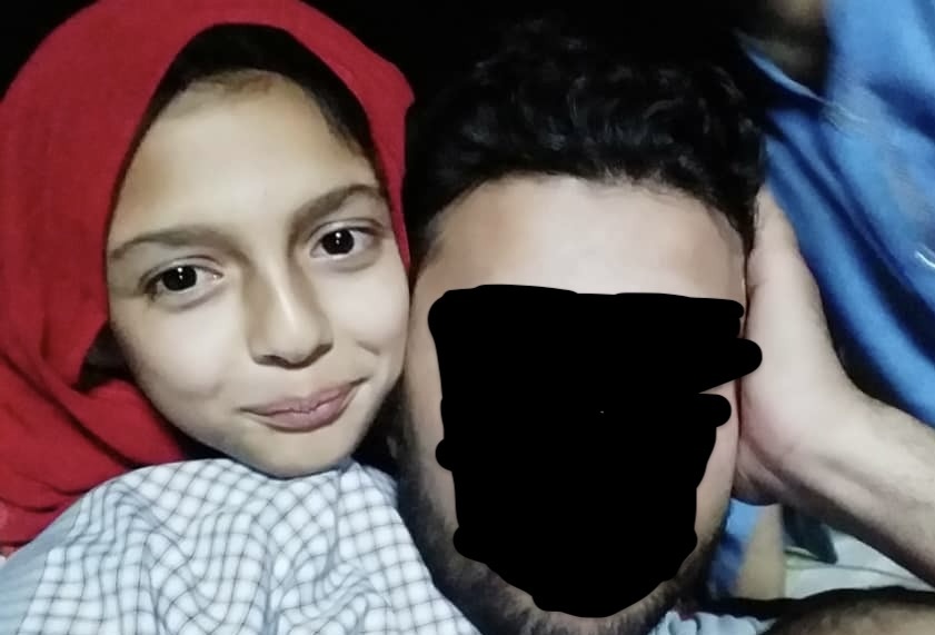 Nazifa, 10, with family member with face obscured for safety reasons.