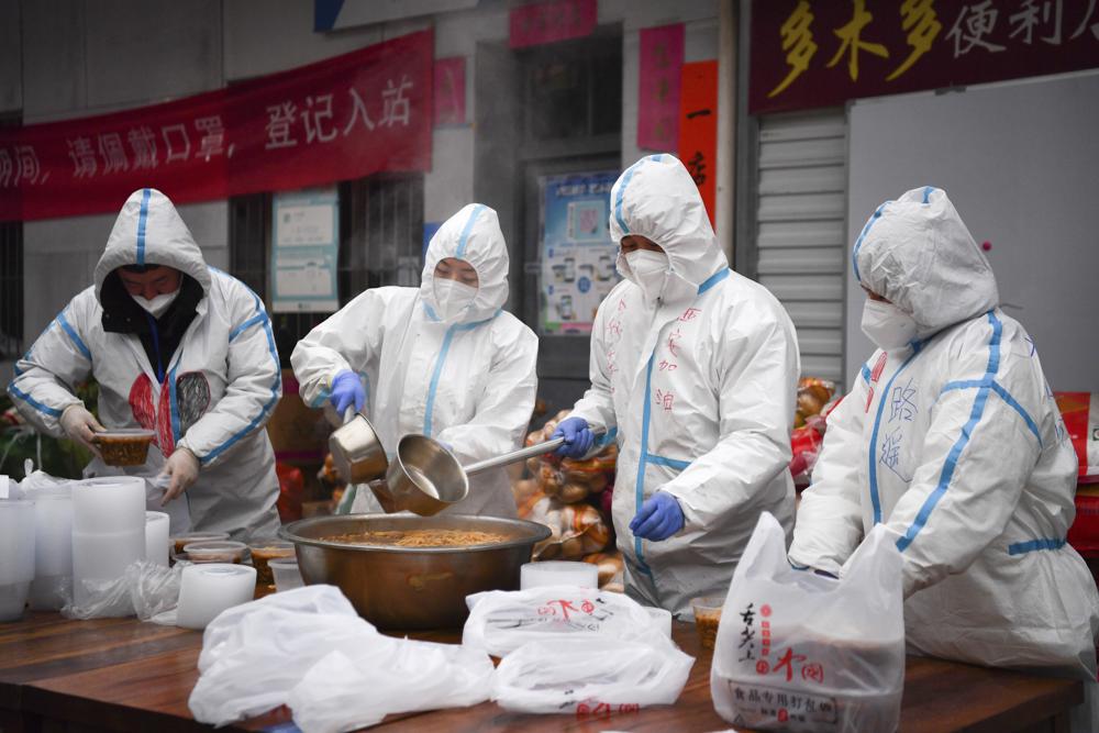 In this photo released by China's Xinhua News Agency, volunteers wearing protective suits package meals for delivery to people under lockdown in Xi'an in northwestern China's Shaanxi Province, Tuesday, Jan. 4, 2022. Hospital officials in the northern Chinese city of Xi'an have been punished after a pregnant woman miscarried after being refused entry, reportedly for not having current COVID-19 test results. (Zhang Bowen/Xinhua via AP).