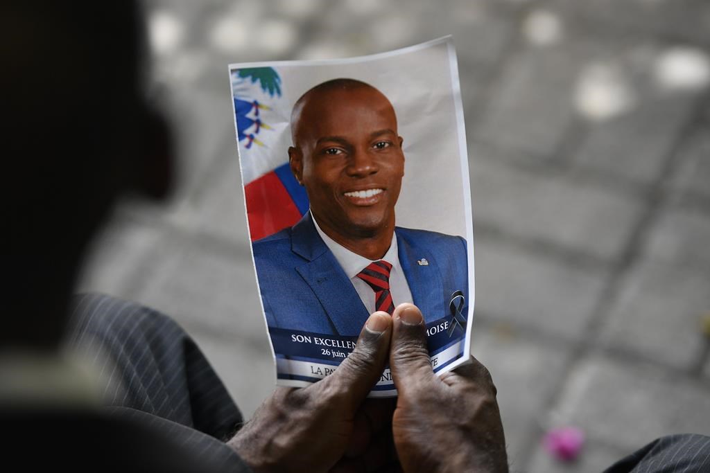 A person holds a photo of late Haitian President Jovenel Moise during his memorial ceremony at the National Pantheon Museum in Port-au-Prince, Haiti, Tuesday, July 20, 2021.  (AP Photo/Matias Delacroix, File).