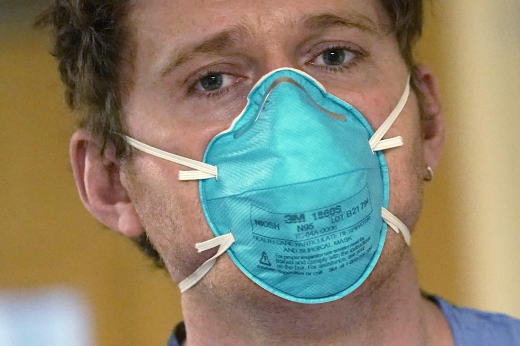 Registered nurse Scott McGieson wears an N95 mask as he walks out of a patient's room in the acute care unit of Harborview Medical Center, Friday, Jan. 14, 2022, in Seattle.