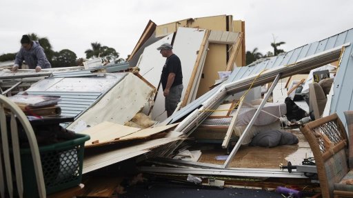 John Finelli, a resident of the Tropicana Mobile Home Park in the Iona area of Fort Myers, Fla., searches for belongings after a tornado destroyed his home on Sunday, Jan. 16, 2022. His parents were in the home and were transported to the hospital. At left is his sister-in law Jennifer Anthony. (Andrew West/The News-Press via AP)