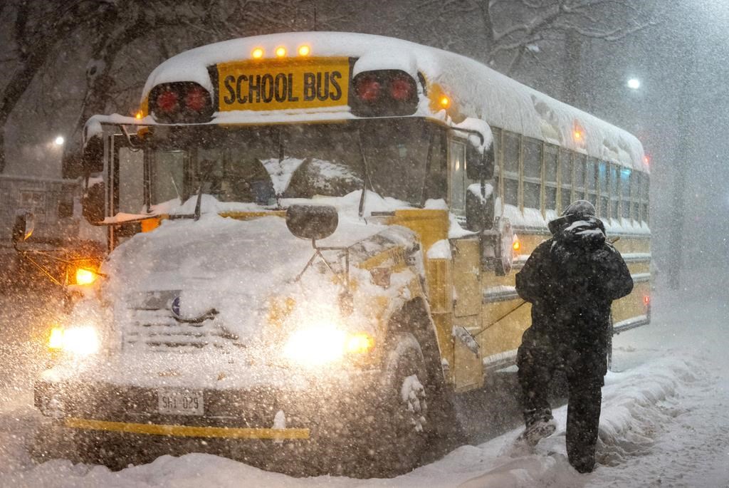 A school bus driver tries to clear snow as a winter storm causes the closure of schools in Toronto on Monday January 17, 2022. 