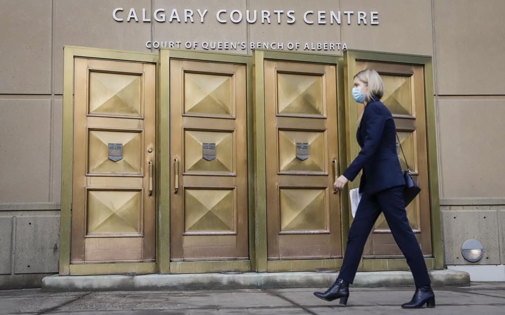 A woman enters the Calgary Courts Centre on Friday, Oct. 30, 2020. Three Calgary men charged with first-degree murder will be sentenced later this month. THE CANADIAN PRESS/Jeff McIntosh.