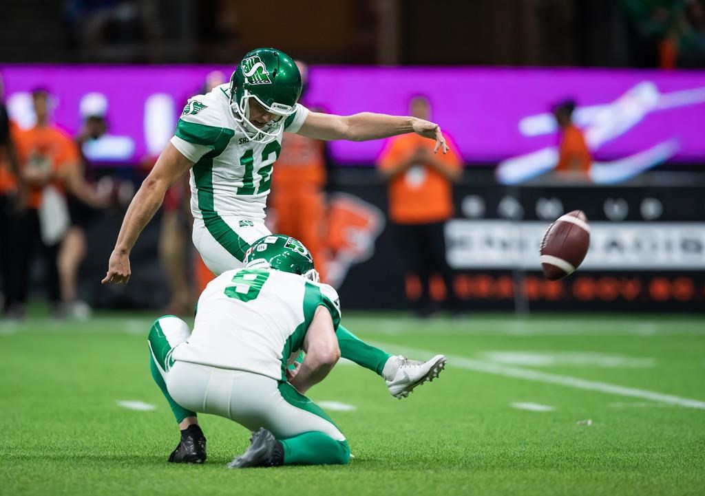 Saskatchewan Roughriders' Brett Lauther (12) kicks the winning convert on a touchdown against the B.C. Lions as Jon Ryan holds during the second half of a CFL football game in Vancouver, on Friday, September 24, 2021. THE CANADIAN PRESS/Darryl Dyck.